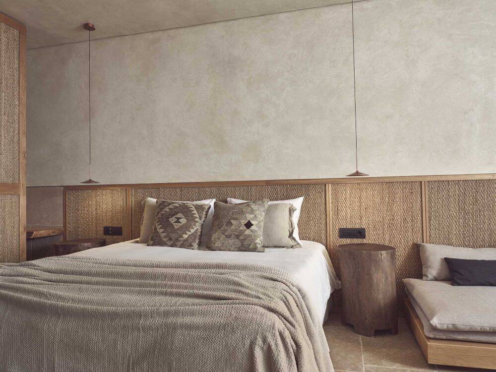 Bedroom inspiration with a woven headboard, layered linen and warm natural wood
